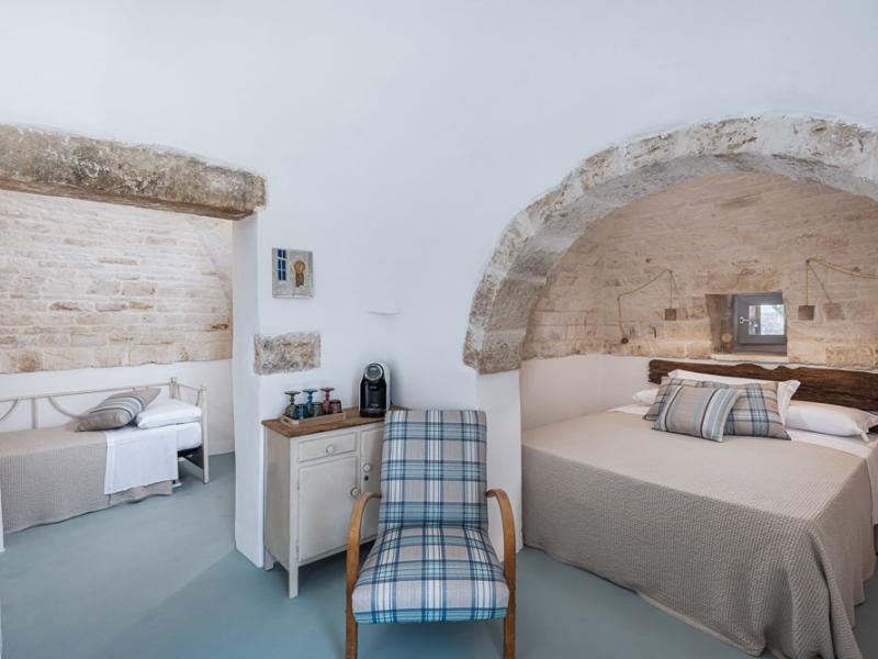 Room with double bed, single bed, and rustic stone decor.