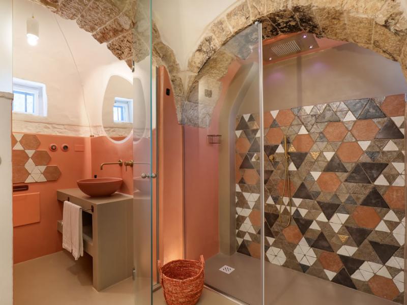 Rustic bathroom with modern shower and colorful geometric tiles.