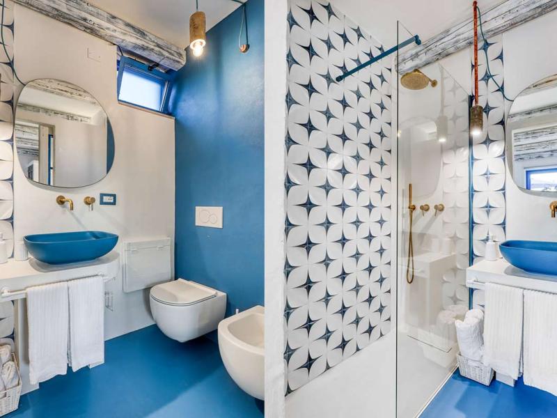 Modern bathroom with geometric tiles, blue sink, and open shower.