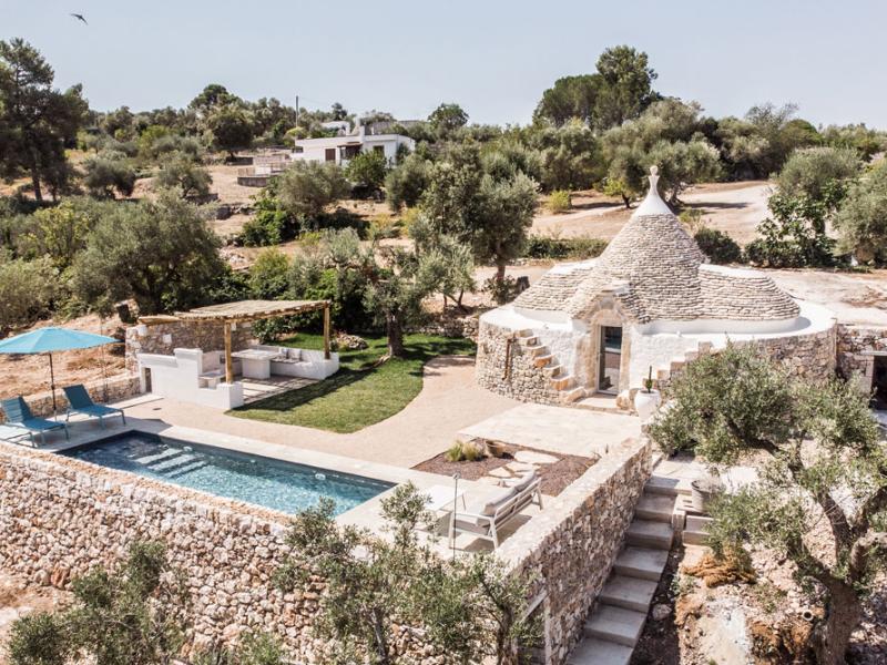 Trullo with pool, garden, and pergola in a rural landscape.