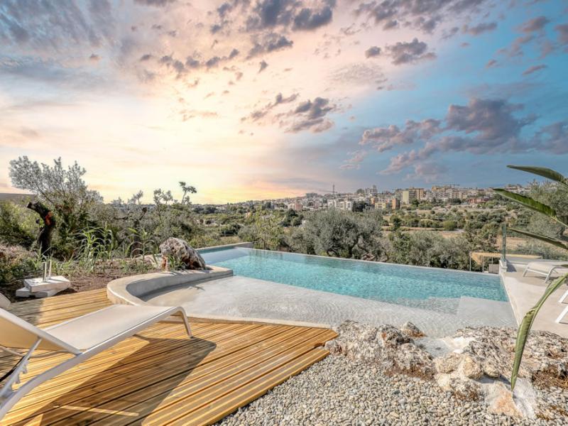 Infinity pool with panoramic city view at sunset.