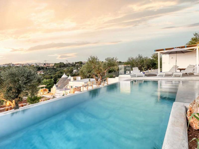 Infinity pool with panoramic view of a city and surrounding hills.