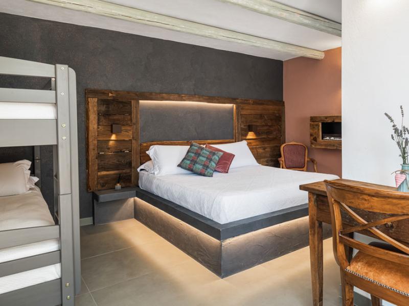 Camera moderna con letto matrimoniale, letto a castello e scrivania in legno.